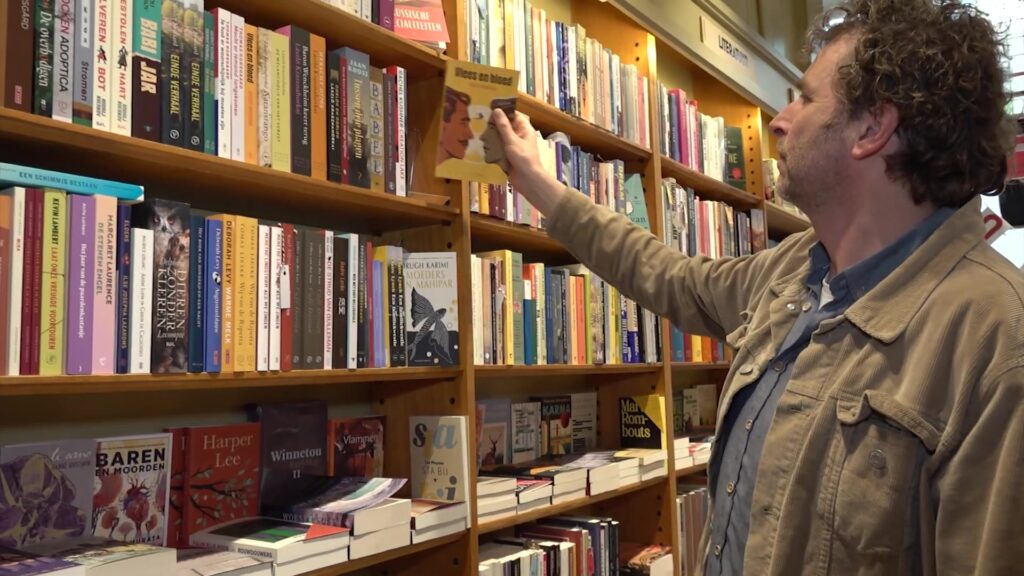 Klant pakt een boek uit de kast in een boekhandel tijdens de Boekenweek