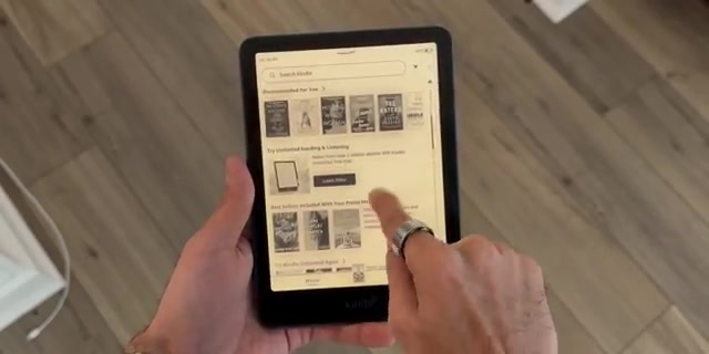Kindle Paperwhite in een hand met de startpagina van de Kindle-winkel op het scherm
