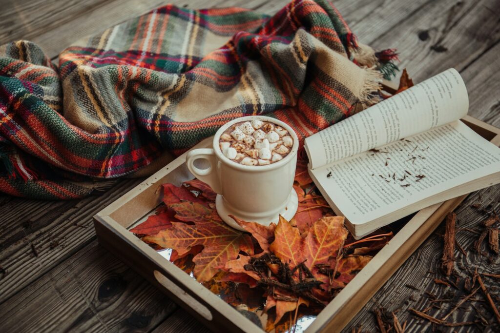 E-reader met een thriller naast een kop thee en een plaid op de bank in de herfst
