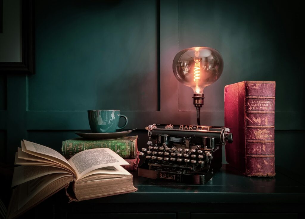 Oude avonturenboeken naast een e-reader op een houten tafel bij lamplicht