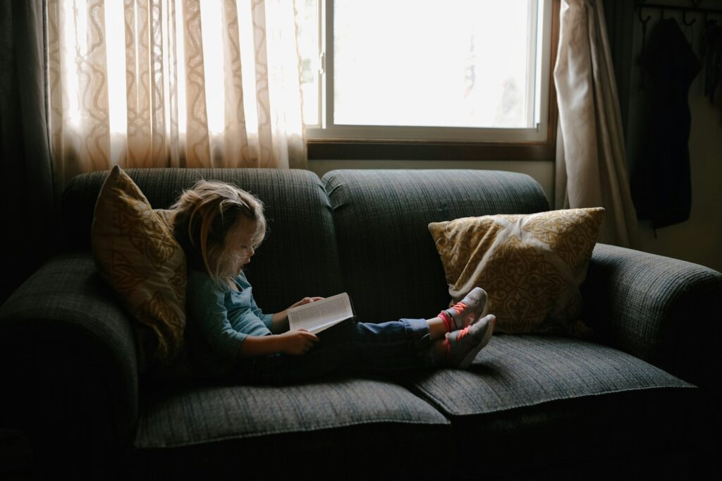 Kind leest op een e-reader met een kleurige hoes op de bank