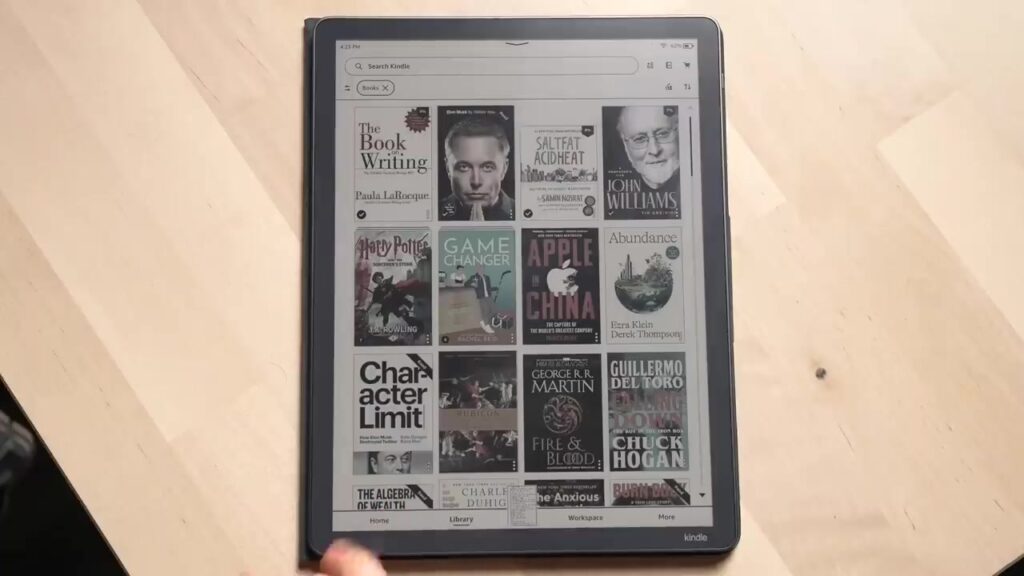 Kindle Scribe Colorsoft met een bibliotheek vol kleurige boekomslagen op een houten tafel