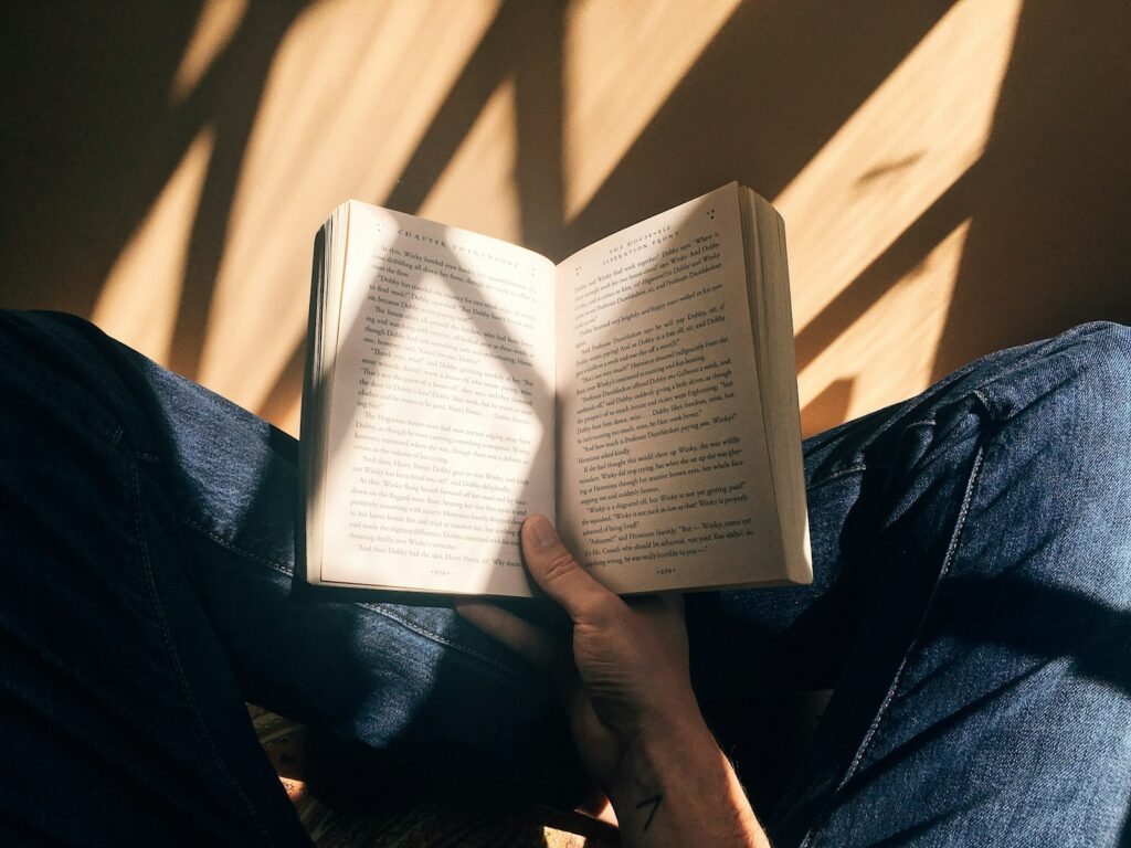 Iemand leest op een e-reader in een stoel bij de boekenkast