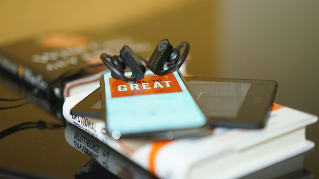 Telefoon met een luisterboek-app en een koptelefoon op tafel