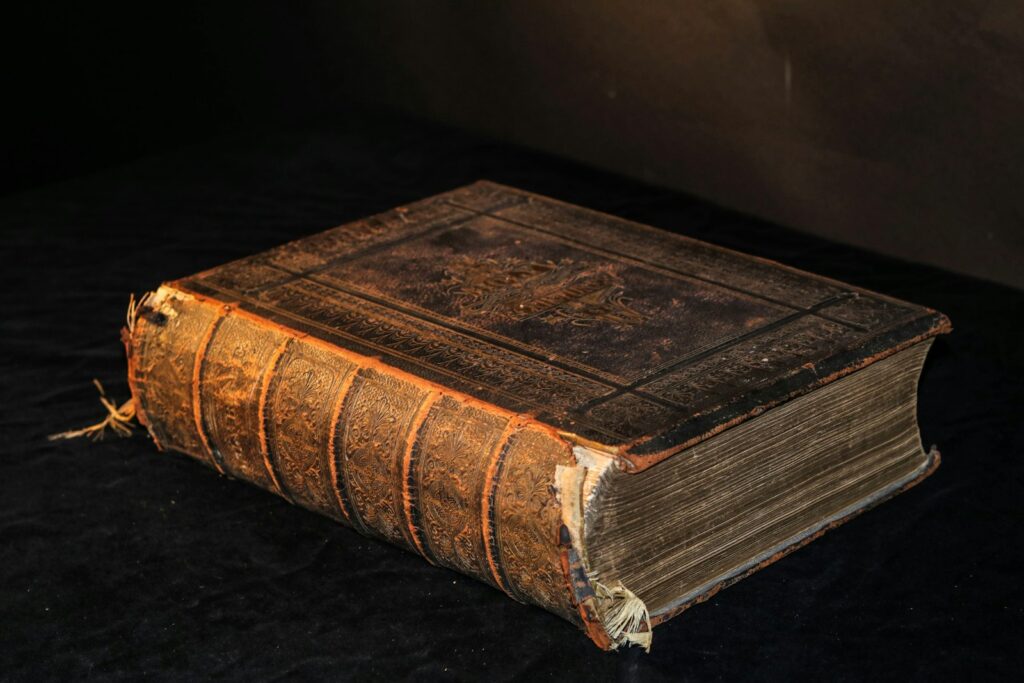 Oud gebonden boek naast een e-reader op een houten tafel