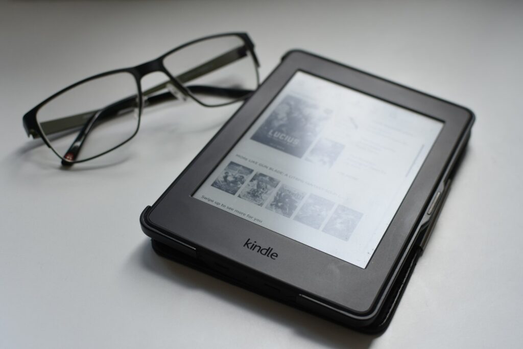 Kindle e-reader op een houten tafel naast een kop thee bij warm lamplicht
