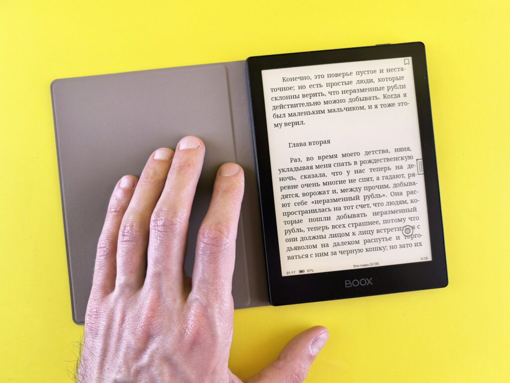 Compacte e-reader van zes inch in de hand naast een kop thee