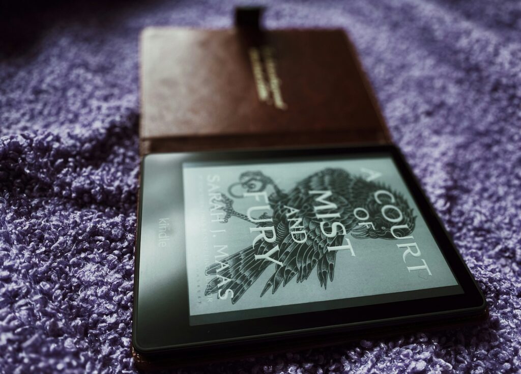 Compacte e-reader met gekleurde achterkant op een stapel boeken