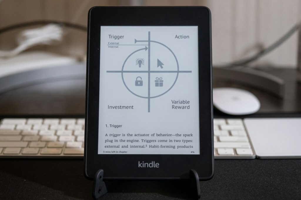 Kindle e-reader naast een laptop met een geopend mailprogramma